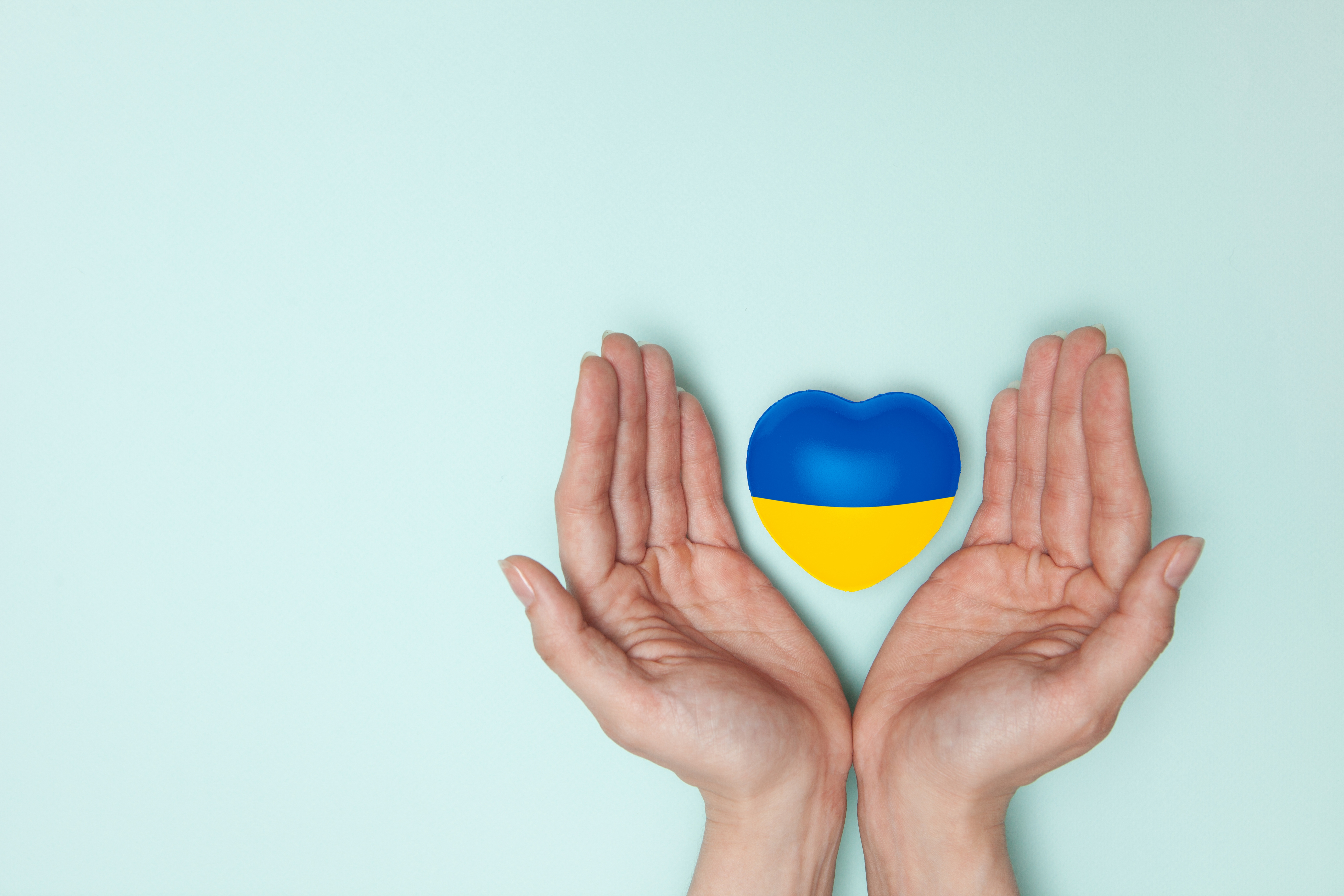Kädet pitävät Ukrainan väreissä olevaa sydäntä