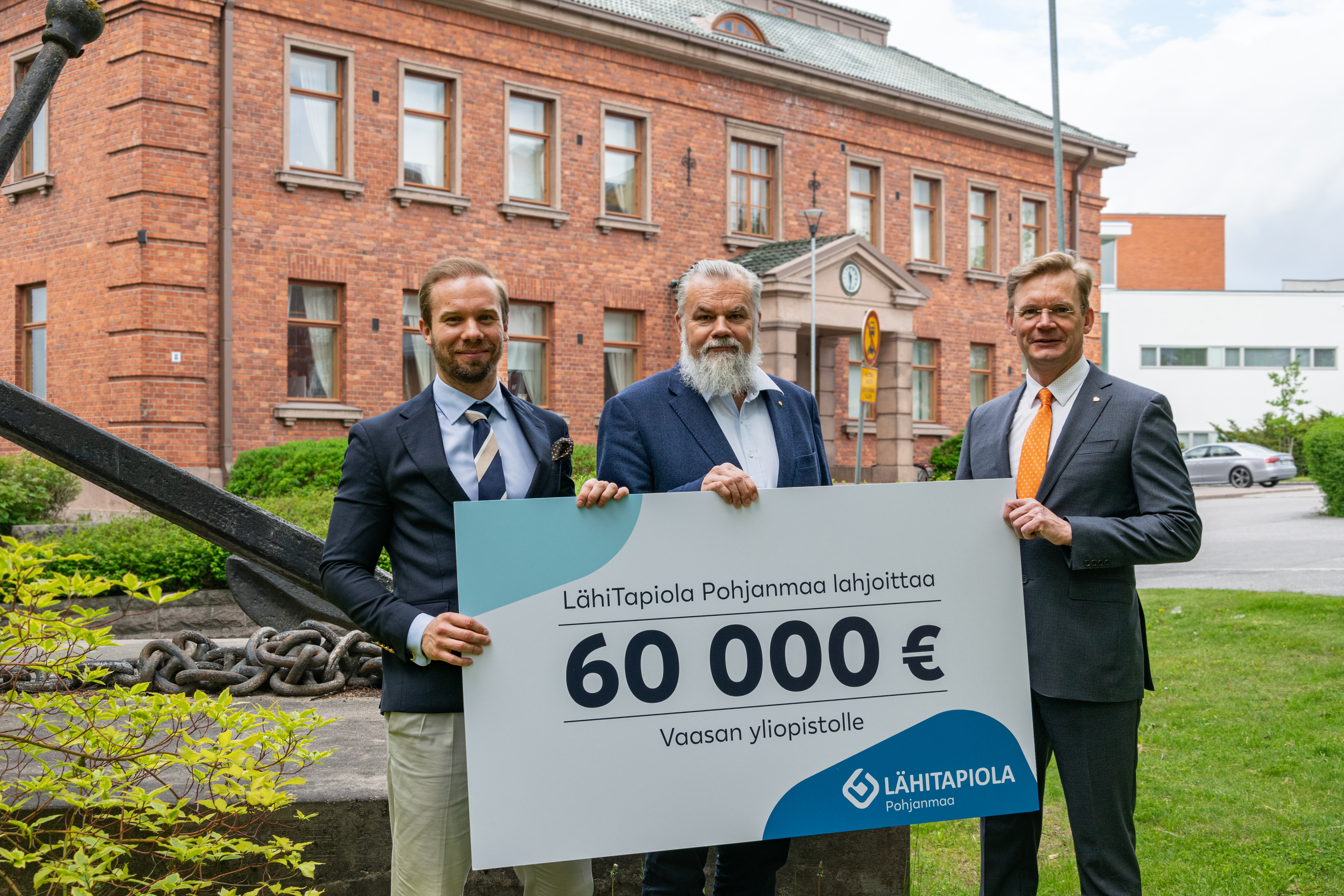 Kuva Joel Sunabackasta, Harry Linnarinteestä ja Jari Kuusistosta Konttorin edessä. He pitelevät 60000 euron lahjoituskylttiä käsissään.