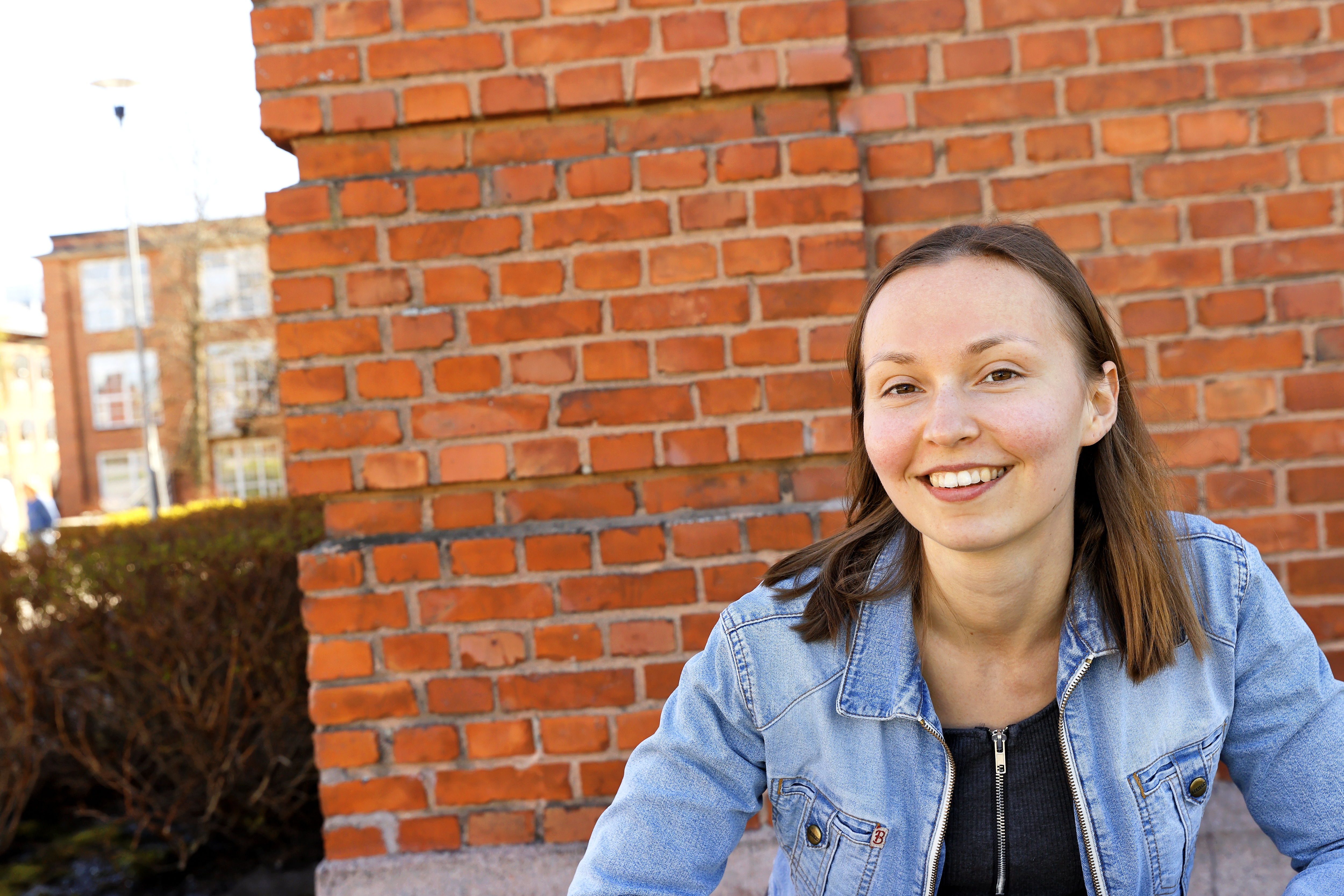 Tyttö hymyilee Konttori-rakennuksen vierellä