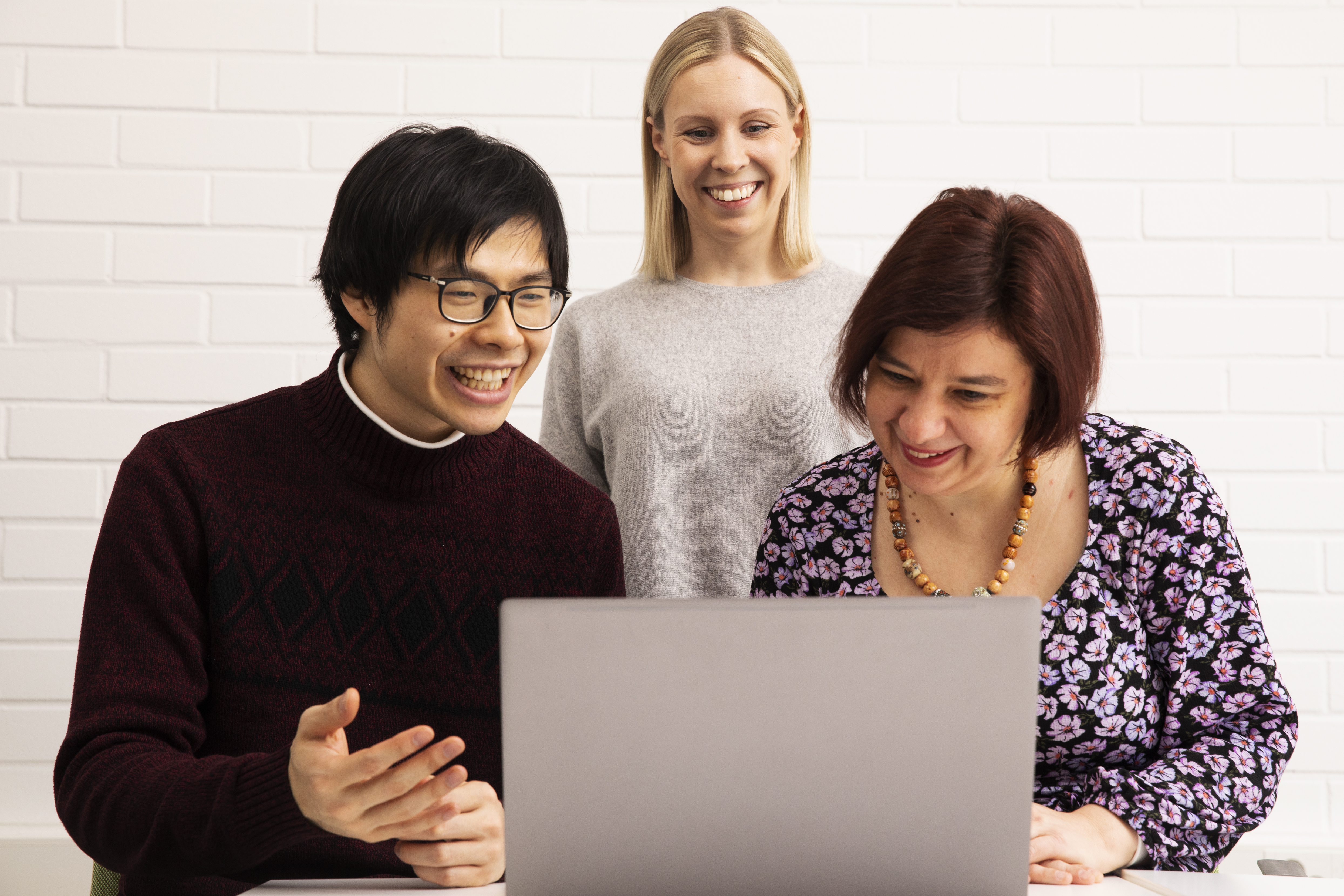 Three people looking at a laptop screen.