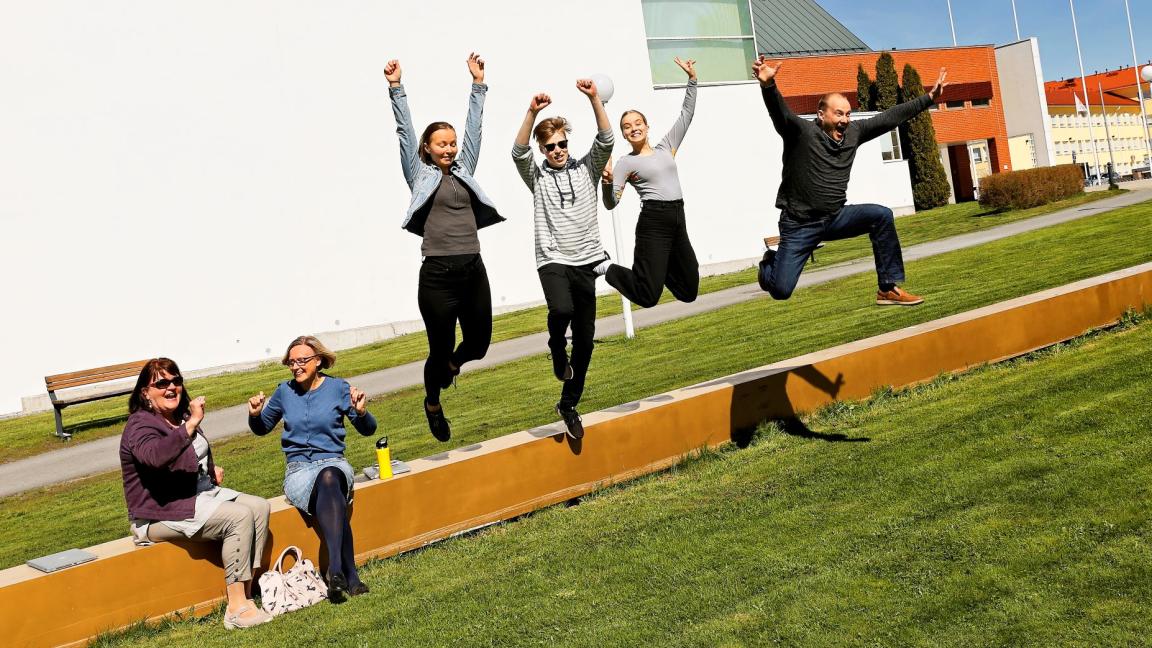 Iloiset opiskelijat hyppäävät penkiltä alas