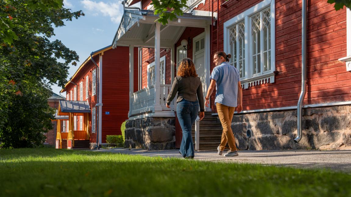 Kaksi ihmistä kävelemässä Vaasan yliopiston Puuvilla-talon edustalla.