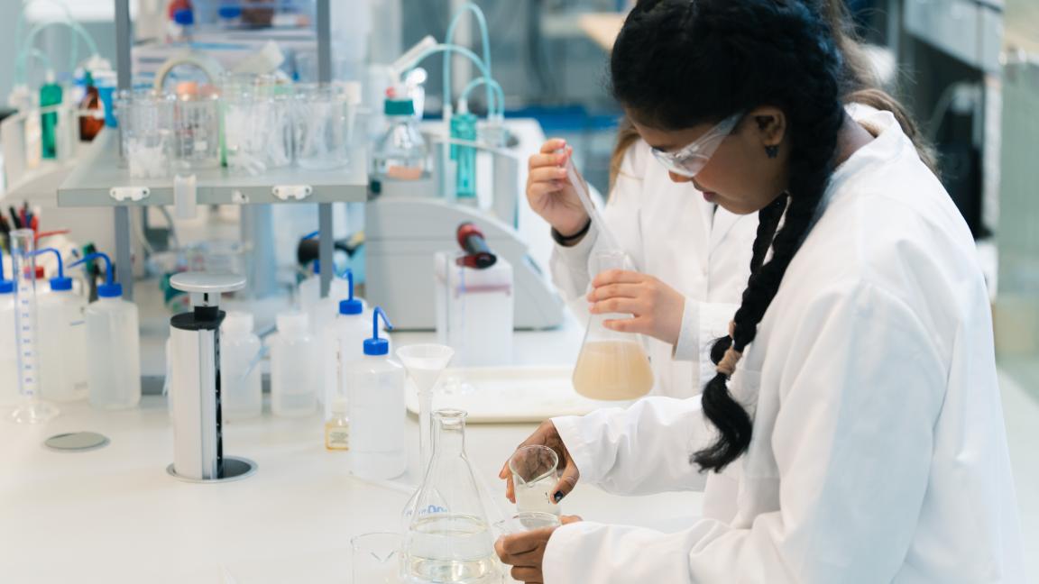 Kaksi nuorta tyttöä tekemässä töitä kemian labroratoriossa