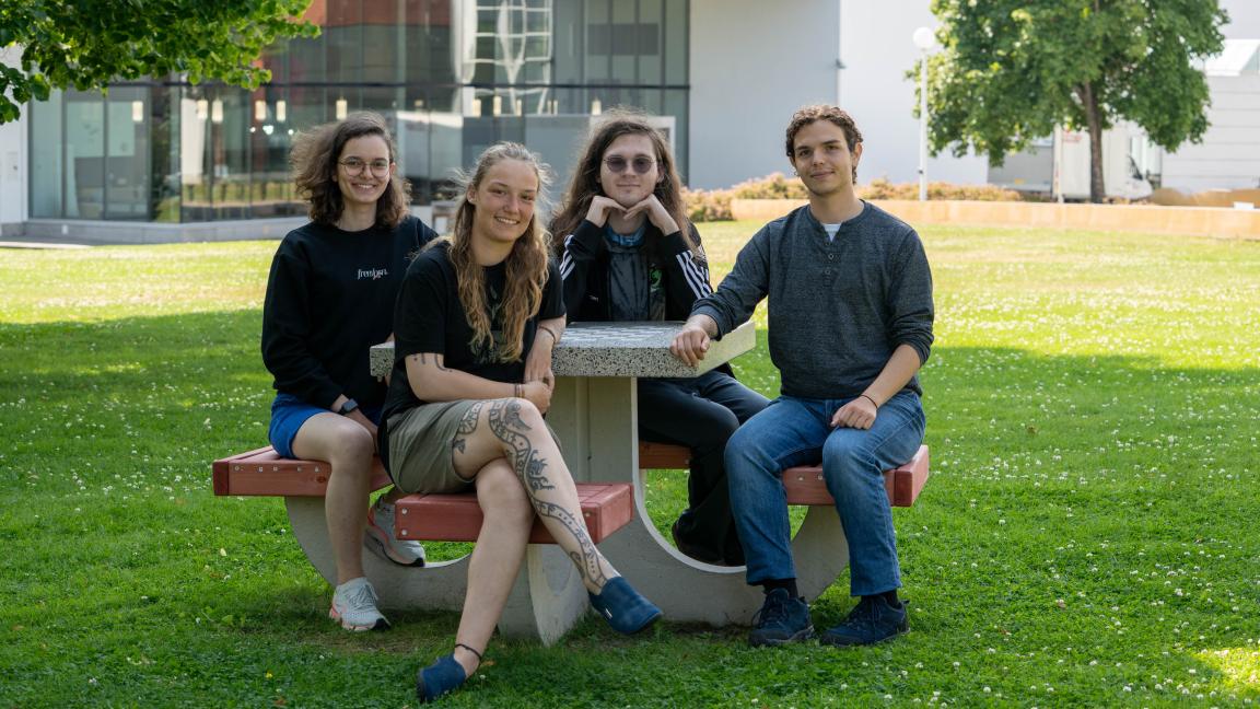 Kesäkouluun osallistuneet Emma, Annika, Ryan ja Rajmond istumassa penkillä Ankkuri-rakennuksen edessä