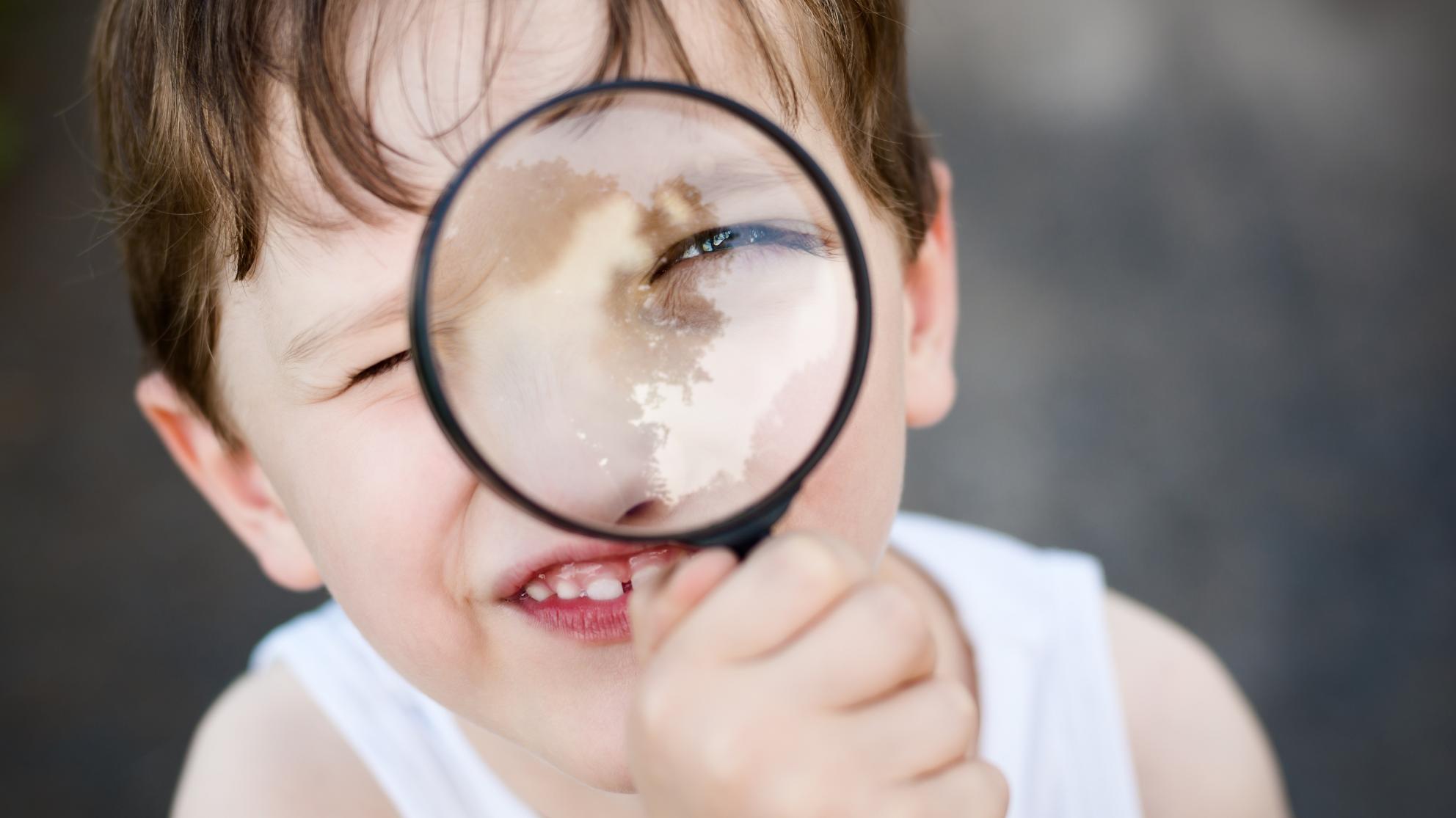lapsi katsoo suurennuslasin läpi