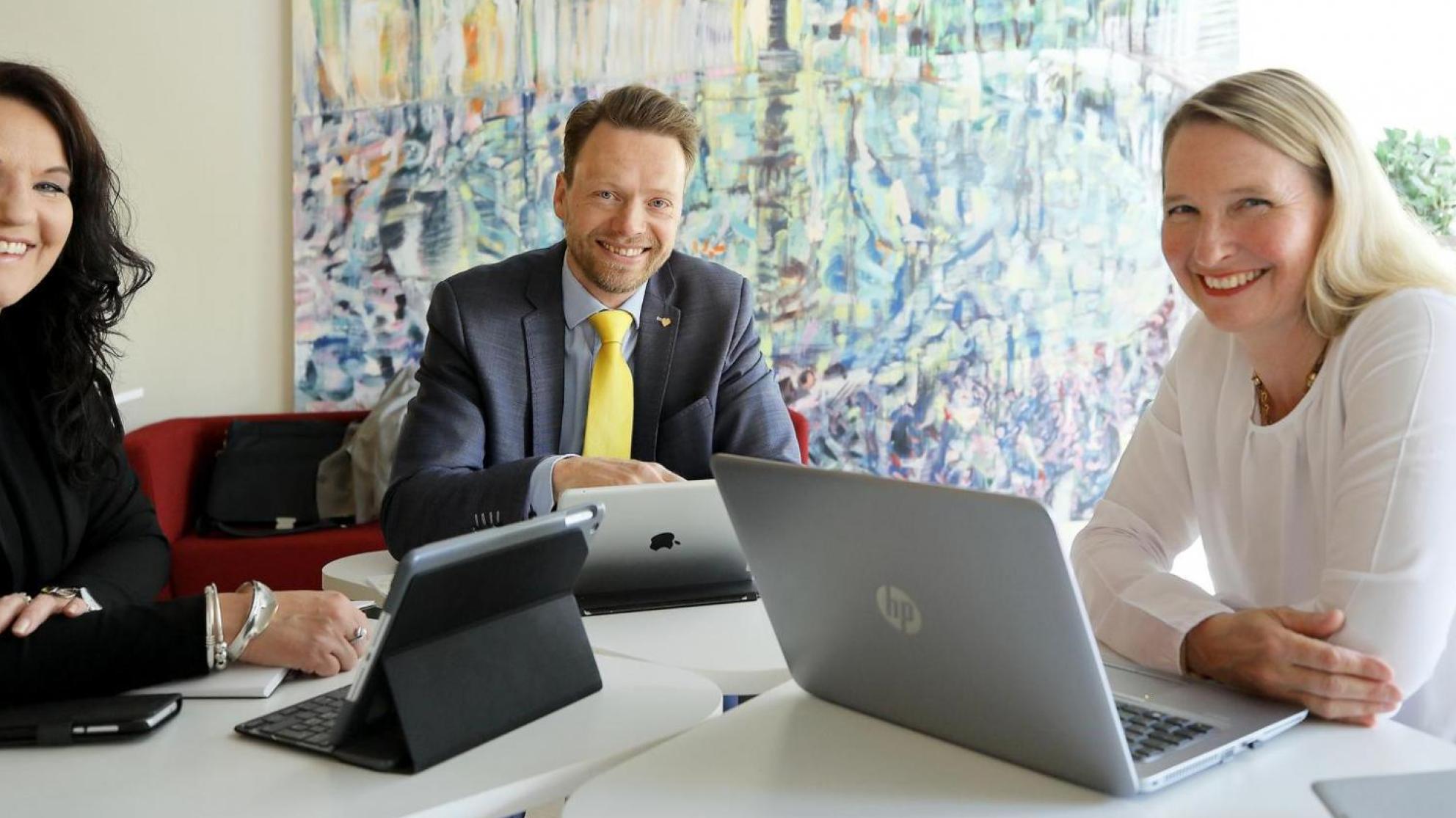 Kolme ihmistä pöydän ympärillä