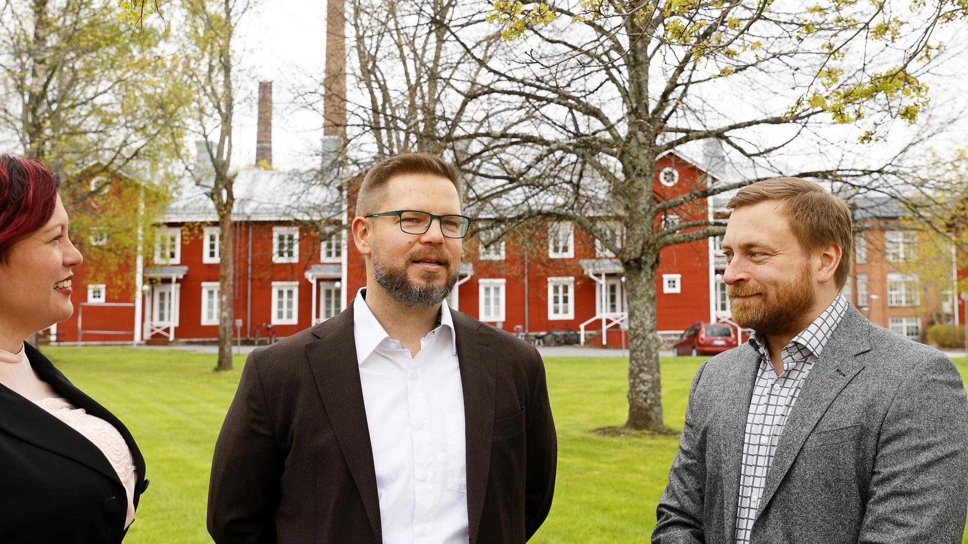 Kolme henkilöä juttelee kampuksella. 