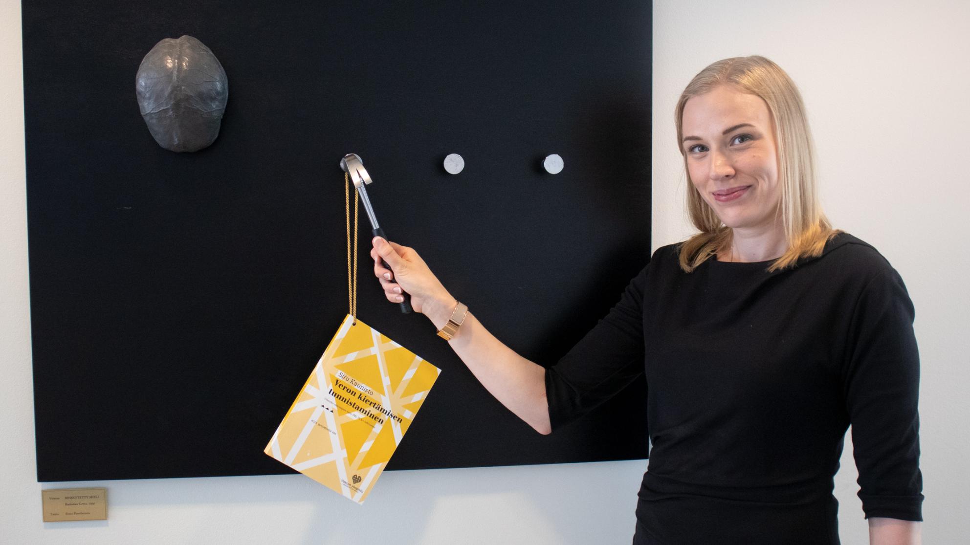 Siru Kaunisto about to nail a copy of her doctoral dissertation to the black board with a hammer