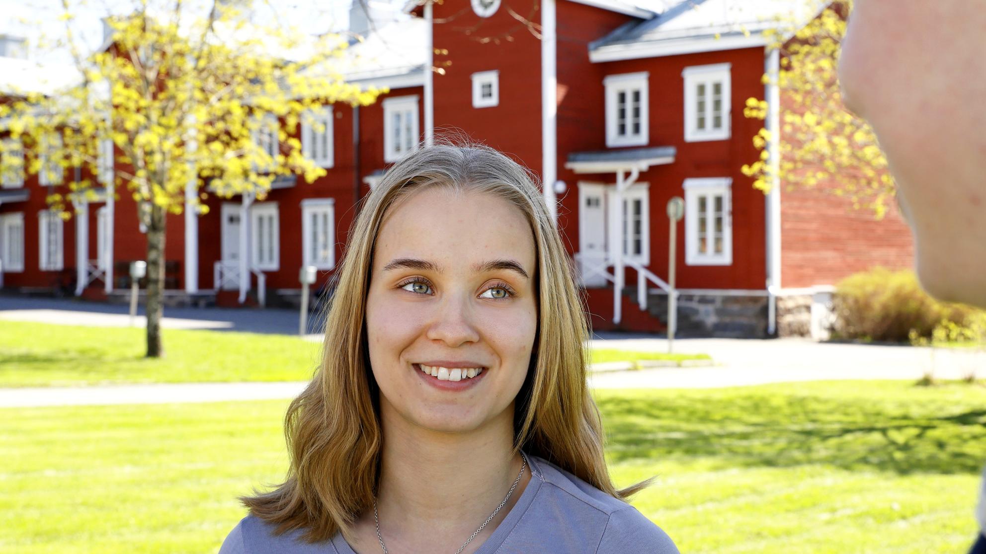 Tyttö hymyilee kampuksella