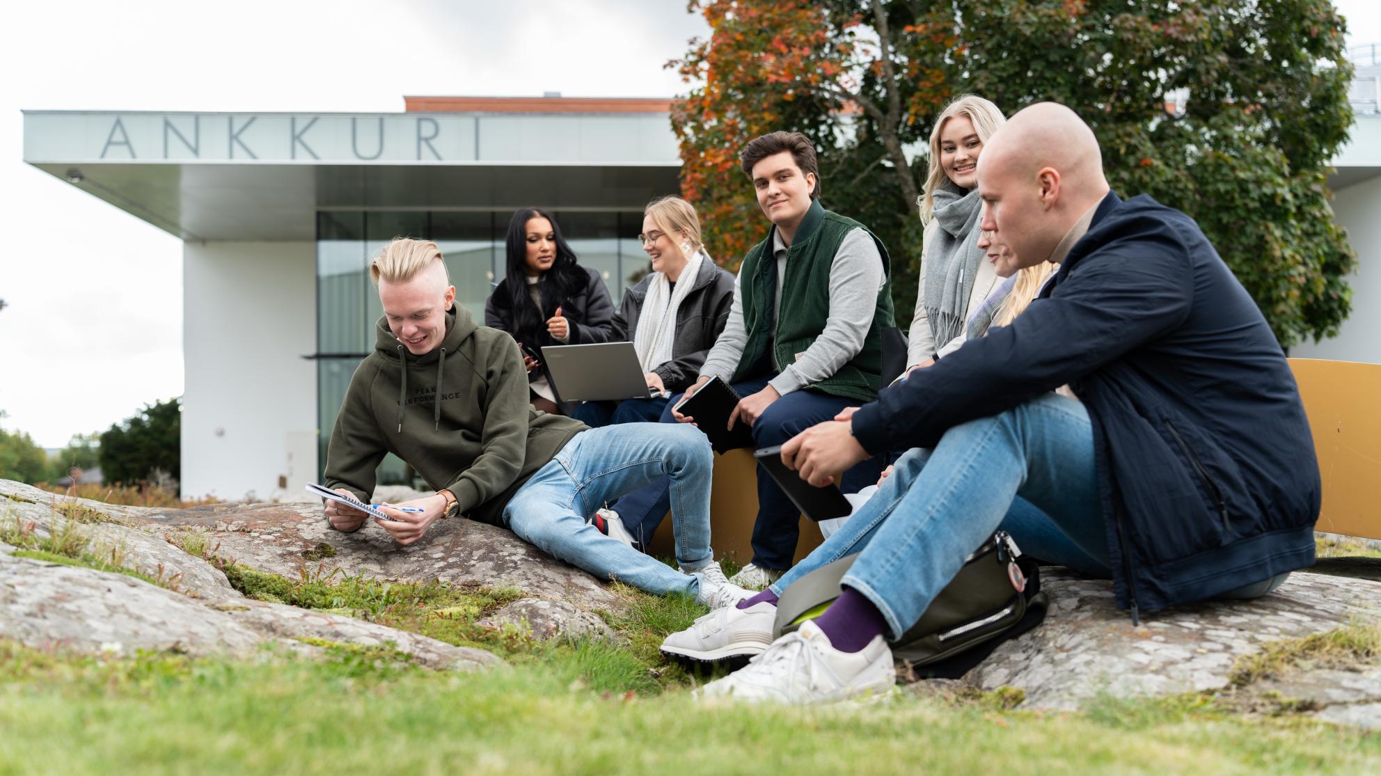 Opiskelijat istuvat kampuksella
