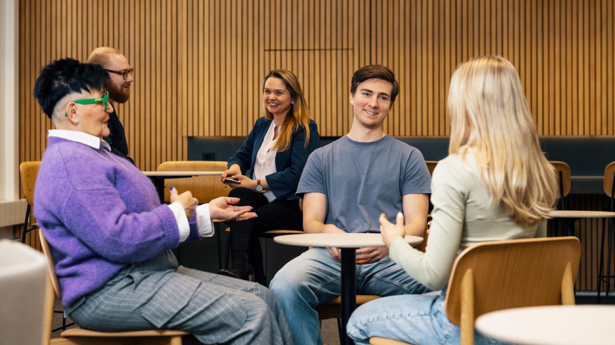 Opiskelijaryhmä keskustelee pöydän ääressä