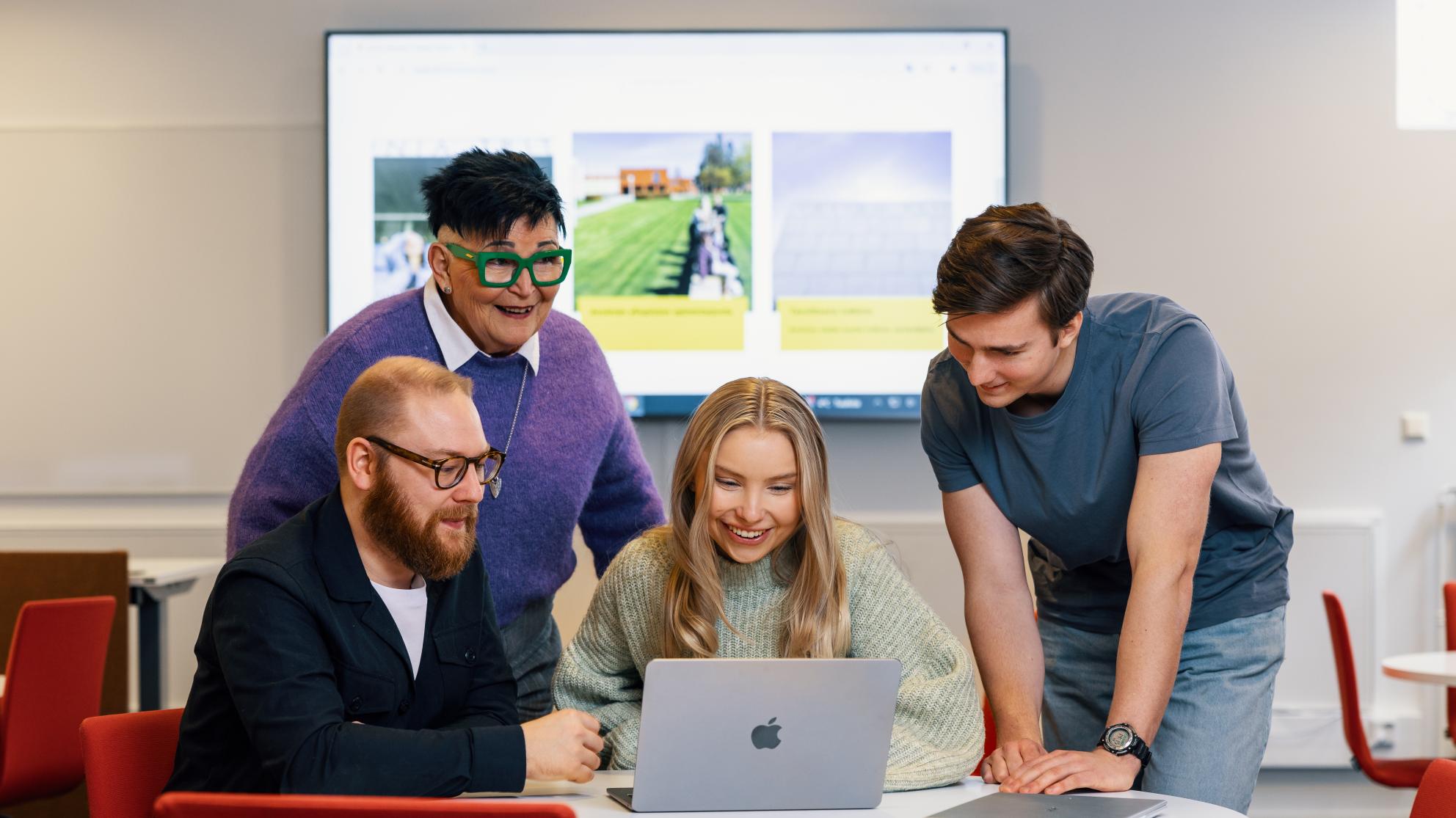 Opiskelijajoukko on kerääntynyt läppärin ääreen työskentelemään