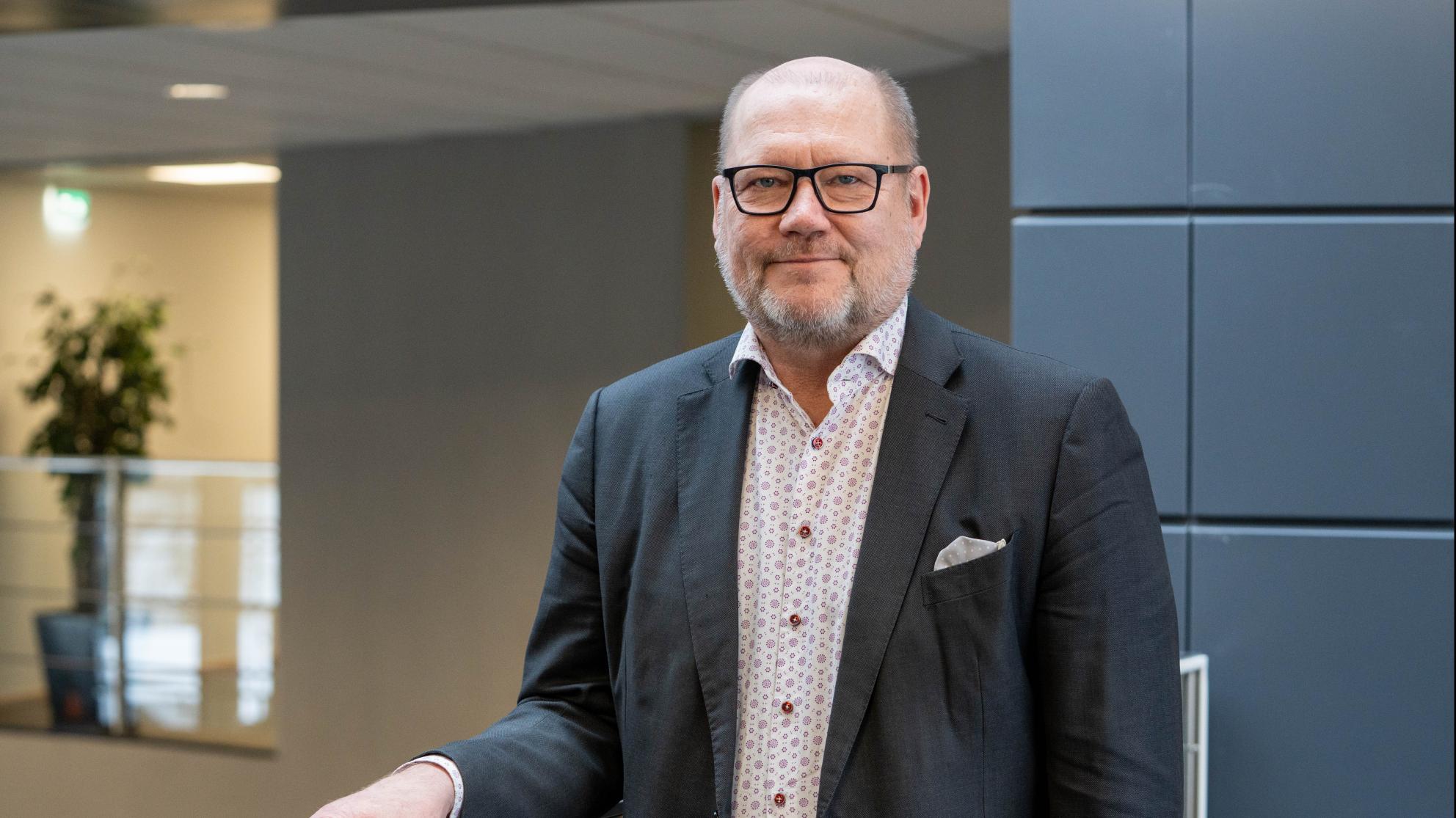 Juha Gröhn nojaa kaiteeseen ja hymyilee kameralle