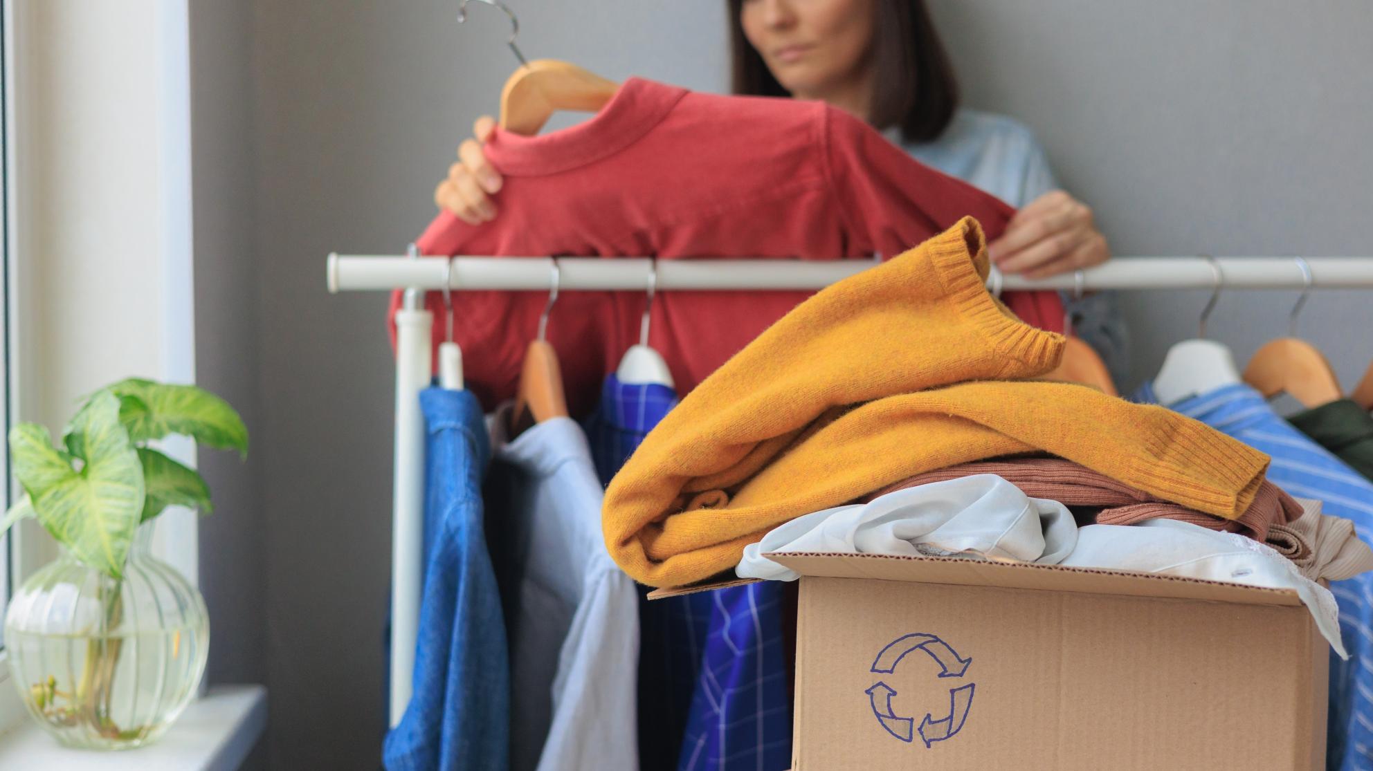 Nainen lajittelemassa vaatteita kierrätykseen