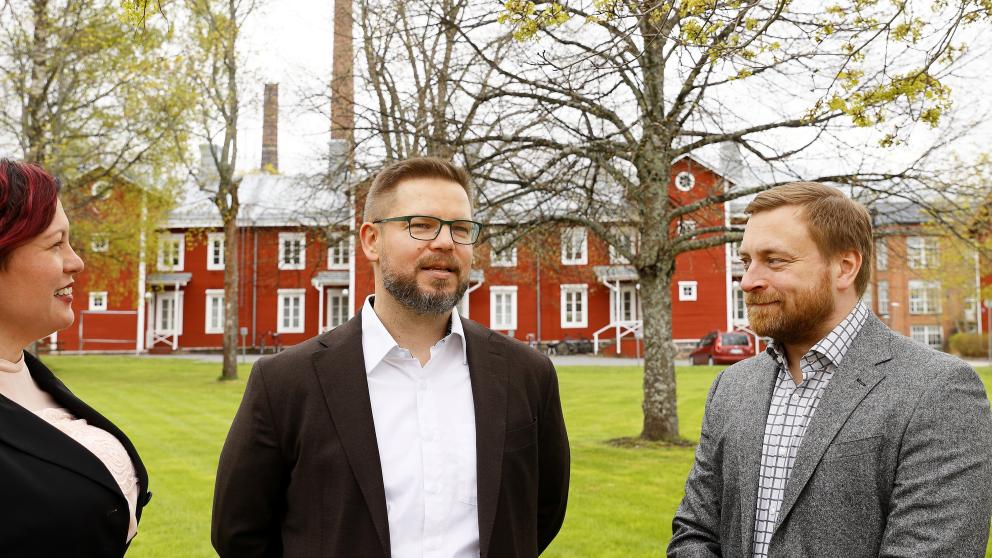 Kolme henkilöä juttelee kampuksella.