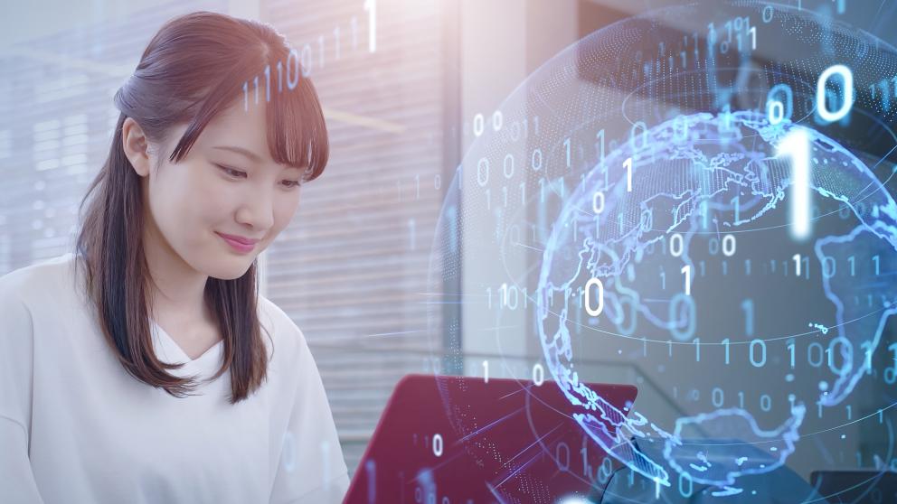 A young woman sitting in front of a laptop, with faded digital numbering overlaying a digital representation of earth.