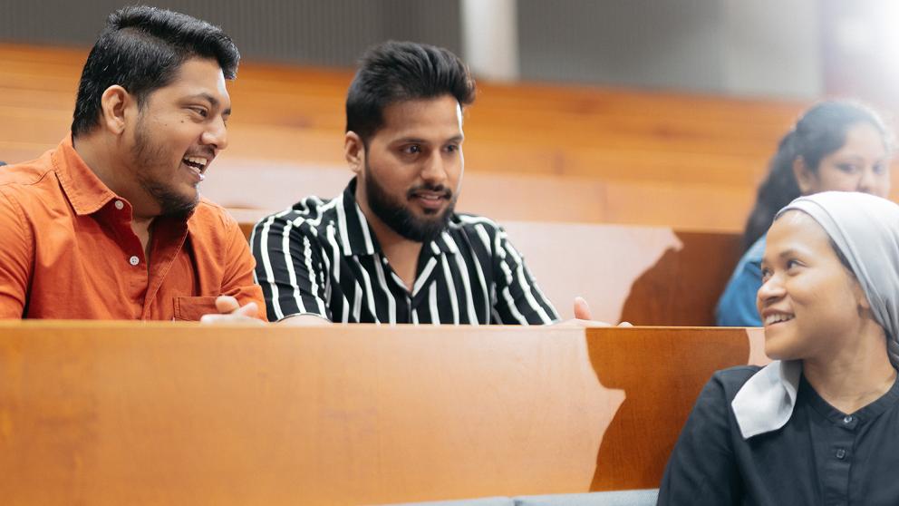 Three students discussing and smiling.