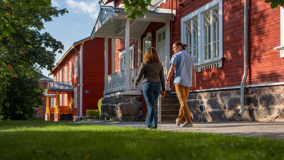Kaksi ihmistä kävelemässä Vaasan yliopiston Puuvilla-talon edustalla.