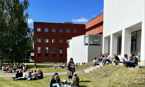 Sunny university campus lawn with staff here and there on a picnic