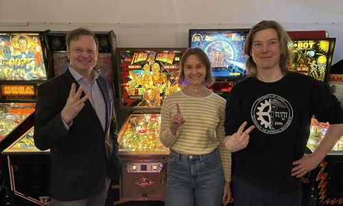 In the picture: Raine Hermans, students Noora Pahkala and Matias Mäkelä. Pinball machines in the background.. 