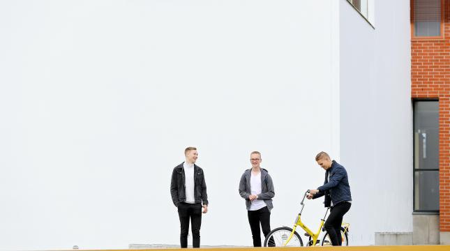 Kolme opiskelijaa kampuksella.