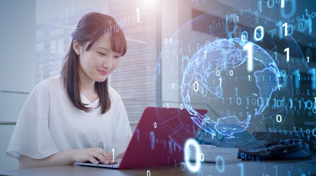 A young woman sitting in front of a laptop, with faded digital numbering overlaying a digital representation of earth.