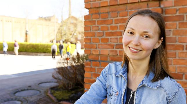 Tyttö hymyilee Konttori-rakennuksen vierellä