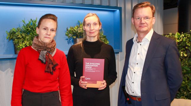 Kirjan julkaisutilaisuus, kolme henkilöä poseeraa kirjan kanssa.