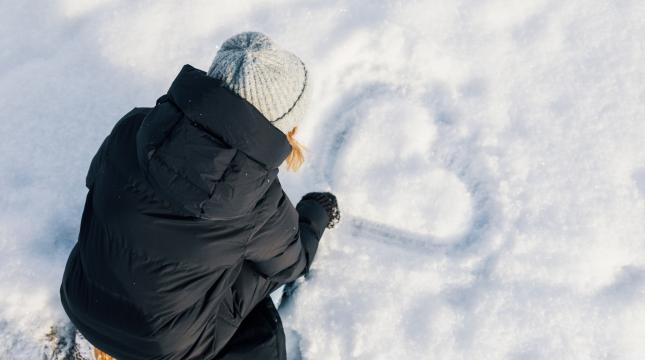 student drawing a heart in snow
