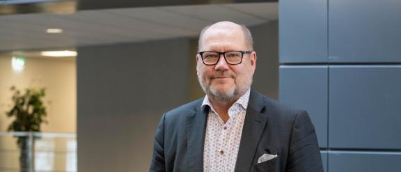 Juha Gröhn nojaa kaiteeseen ja hymyilee kameralle