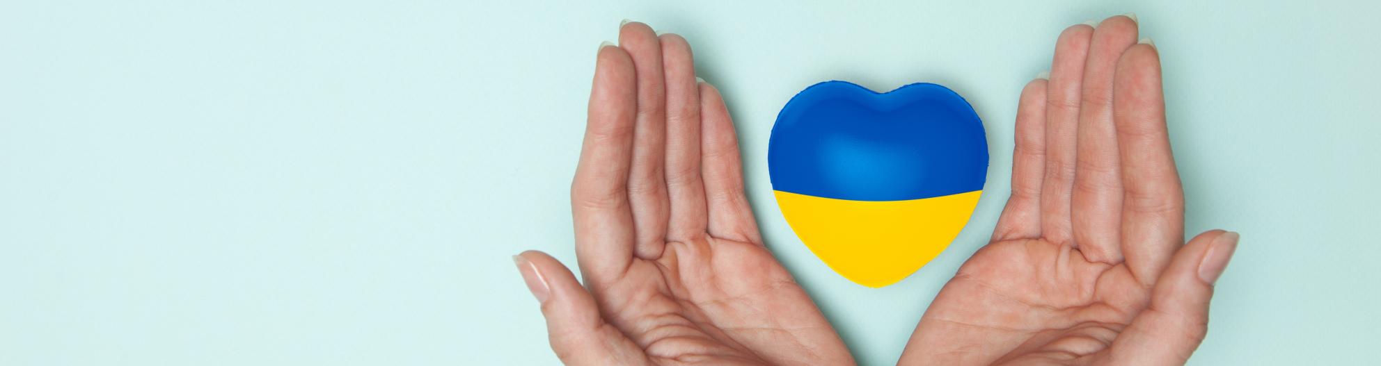Ukrainan väreissä oleva sydän henkilön käsien välissä
