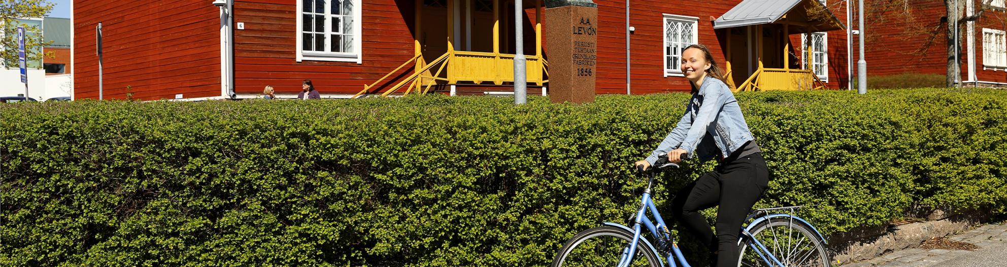 A young woman riding a bicycle at the University of Vaasa campus