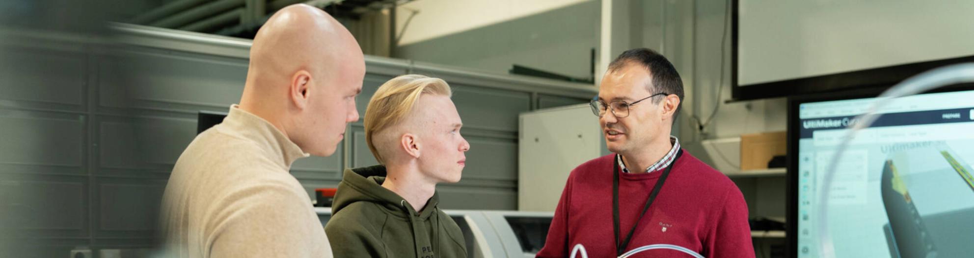 Opettaja ja opiskelijat keskustelevat laboratoriossa. 
