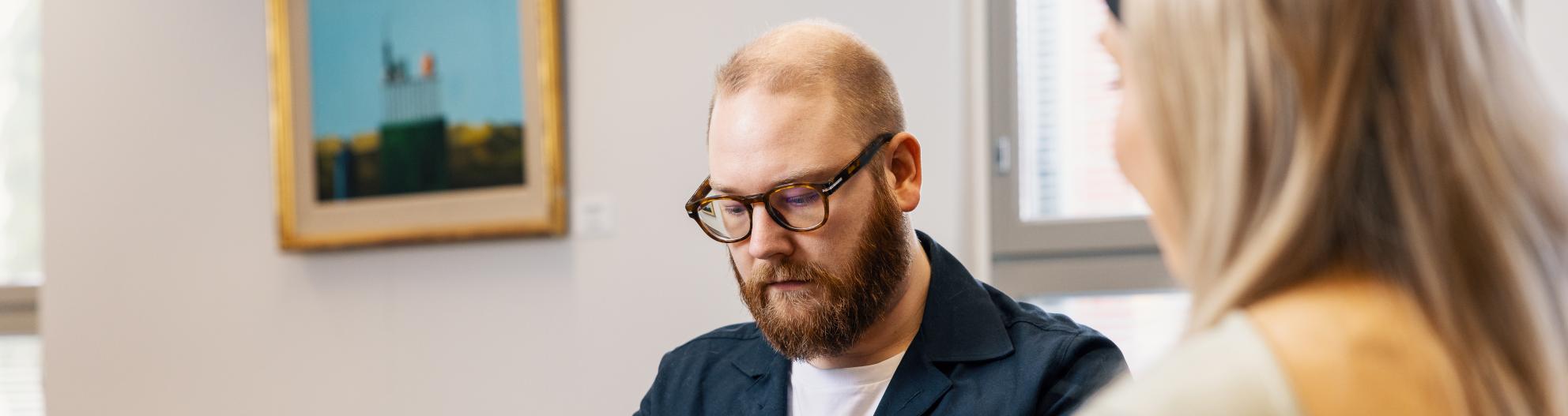 Mies työskentelee läppärillä ja katsoo alaspäin
