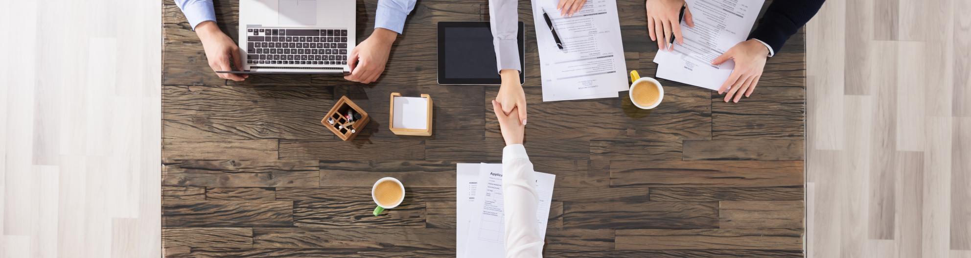 A handshake between employer and new employee over a table. 