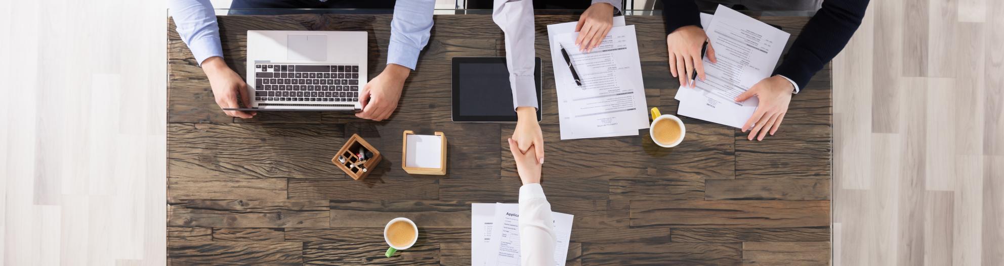 A handshake between employer and new employee over a table. 