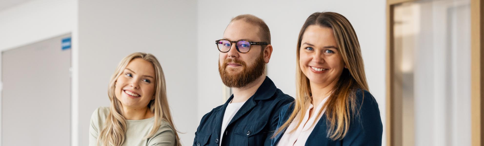 Opiskelijat hymyilevät kaiteseen nojaten ja katsovat kameraan