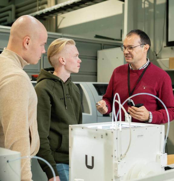 Opettaja ja opiskelijat keskustelevat laboratoriossa.