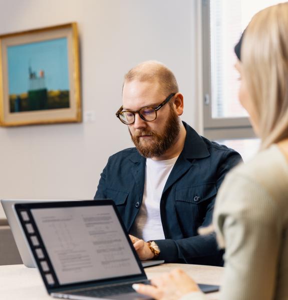 Mies työskentelee läppärillä ja katsoo alaspäin