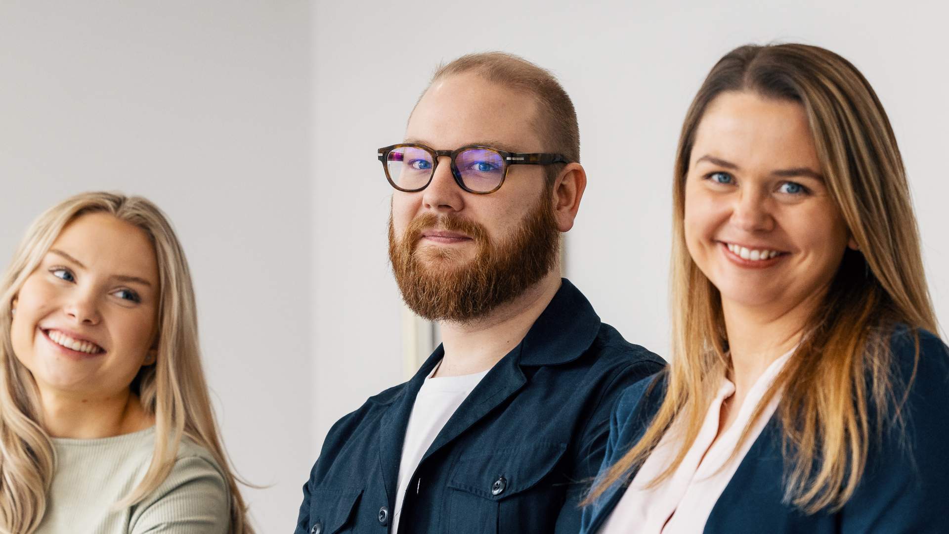  Opiskelijat hymyilevät kaiteseen nojaten ja katsovat kameraan