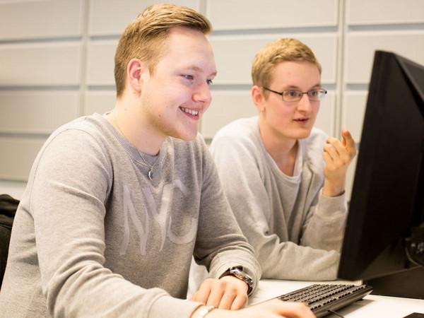 Kaksi opiskelijaa tietokoneella. 