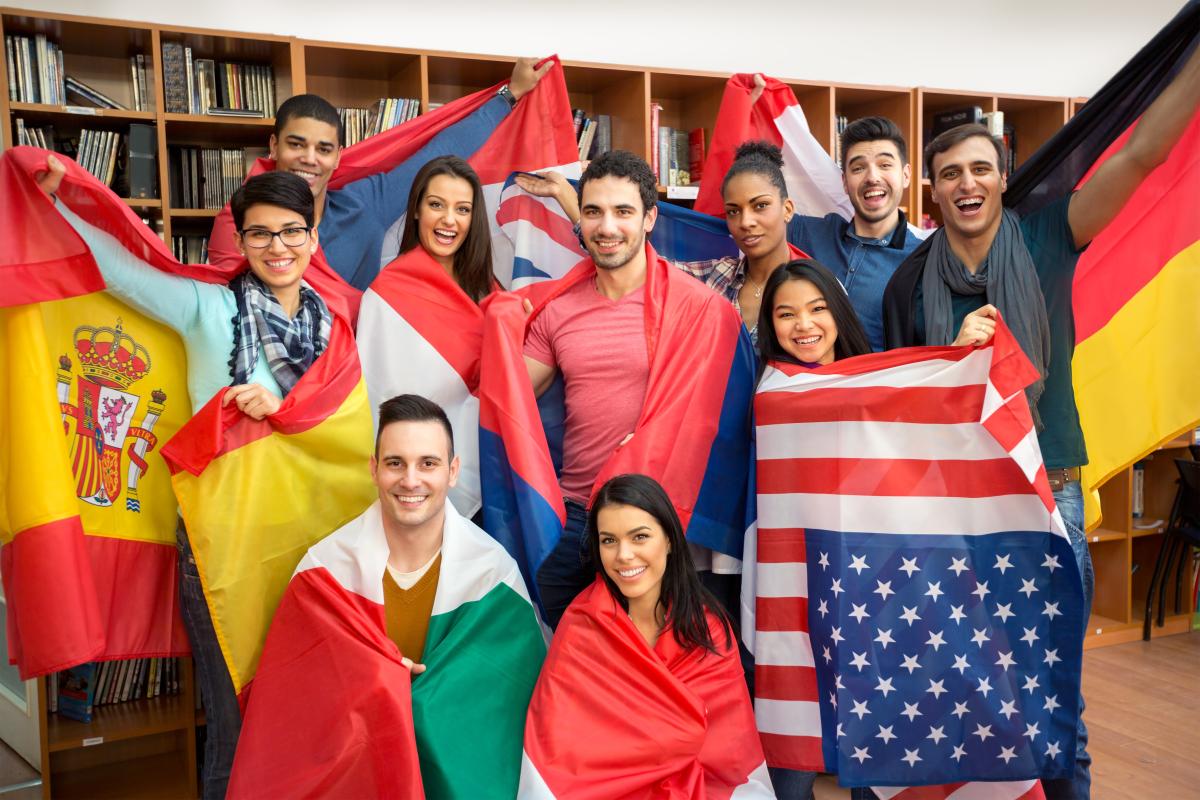 A group of international students holding flags of several countries
