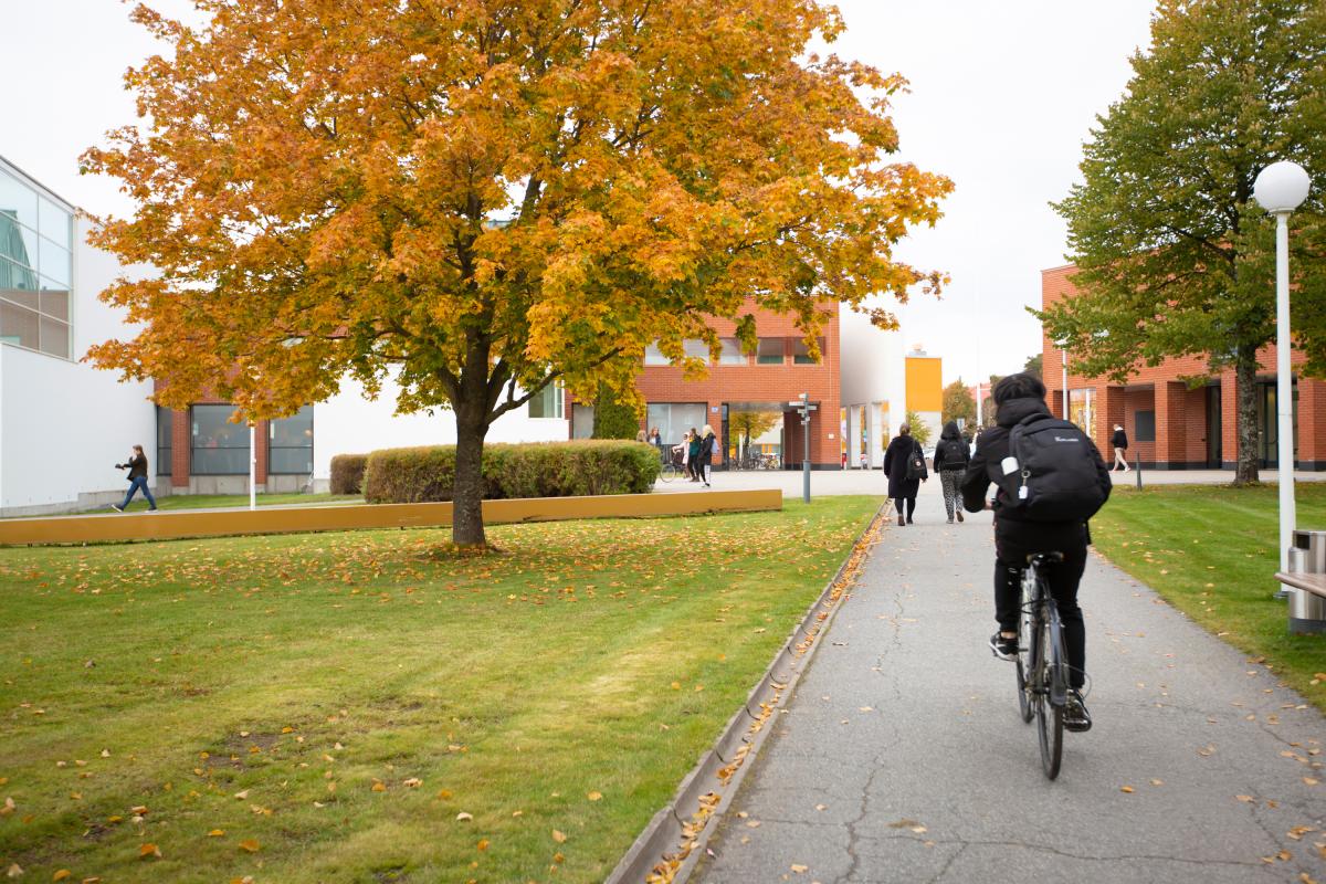 A cyclist with a backbag on the campus in the autumn