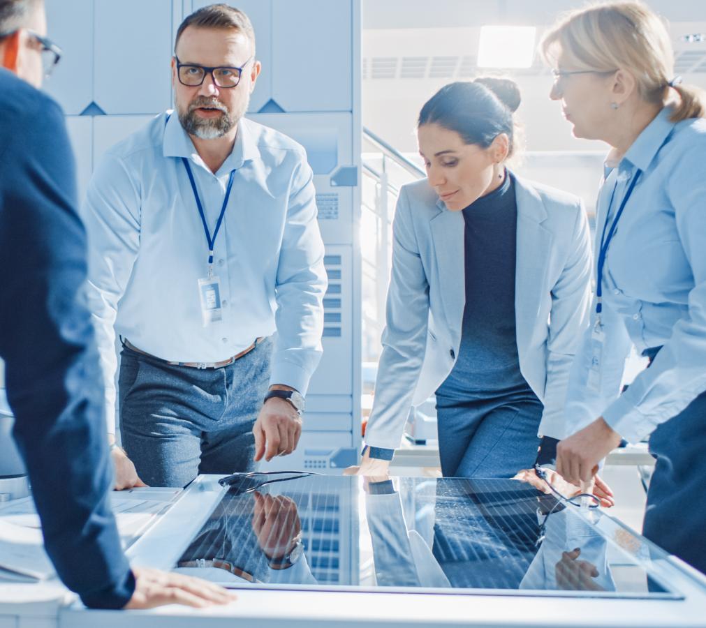 A group of people huddled over a smart table in a modern office