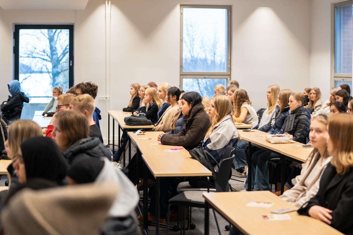 Henkilöitä istumassa luokkahuoneessa ja kuuntelemassa luentoa.