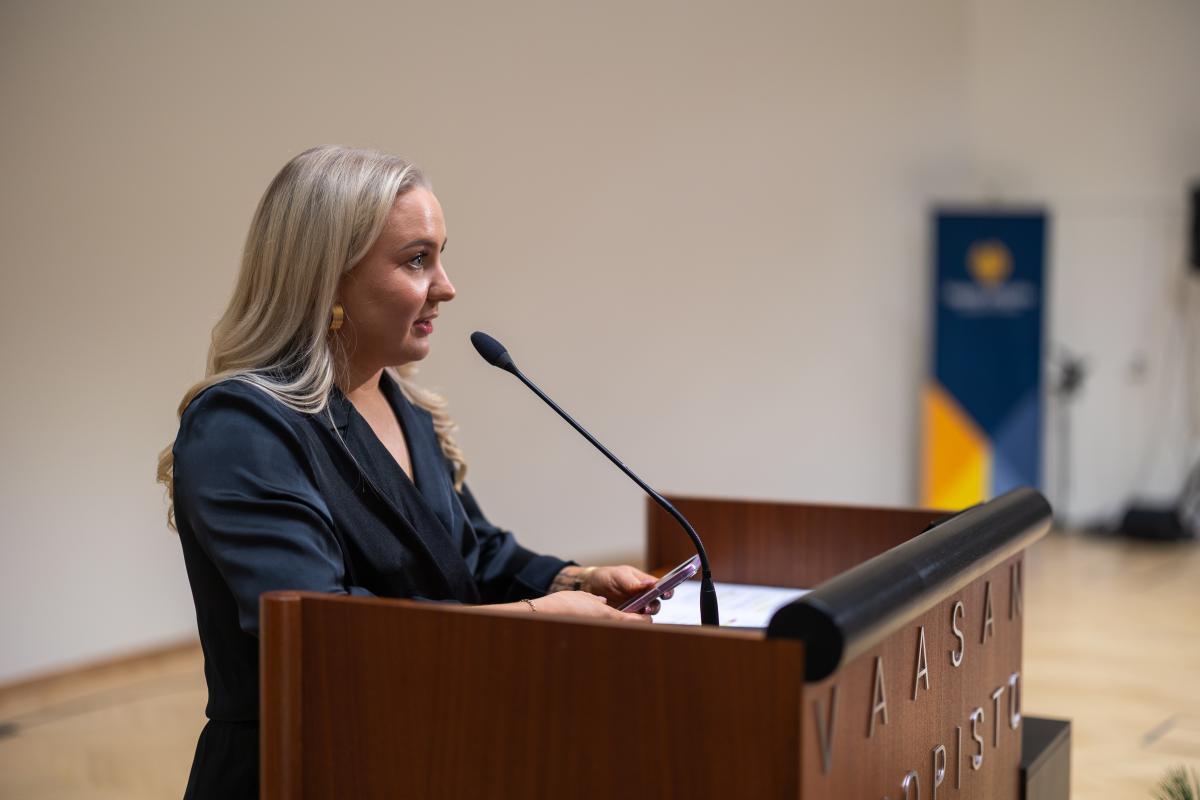 Valmistuva opiskelija Henna Halmela seisomassa puhujanpöntössä ja pitämässä puhetta.