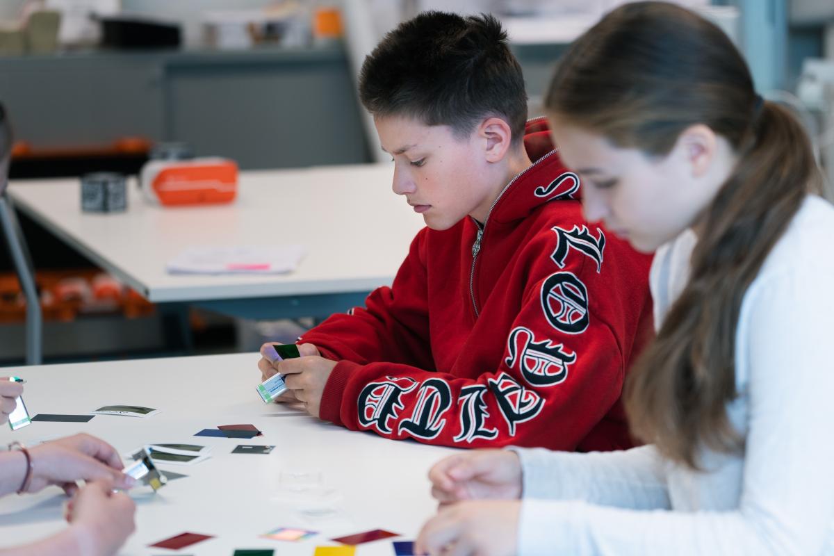 Nuoret istuvat pöydässä ja miettivät tutkivat värilevyjä