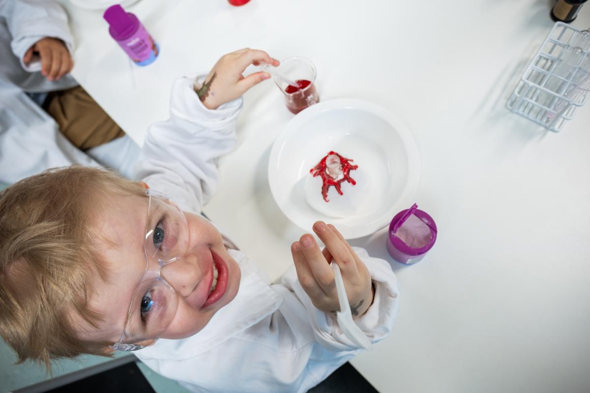 Lapsi tekemässä tiedekoetta suojalasit ja labratakki päällä