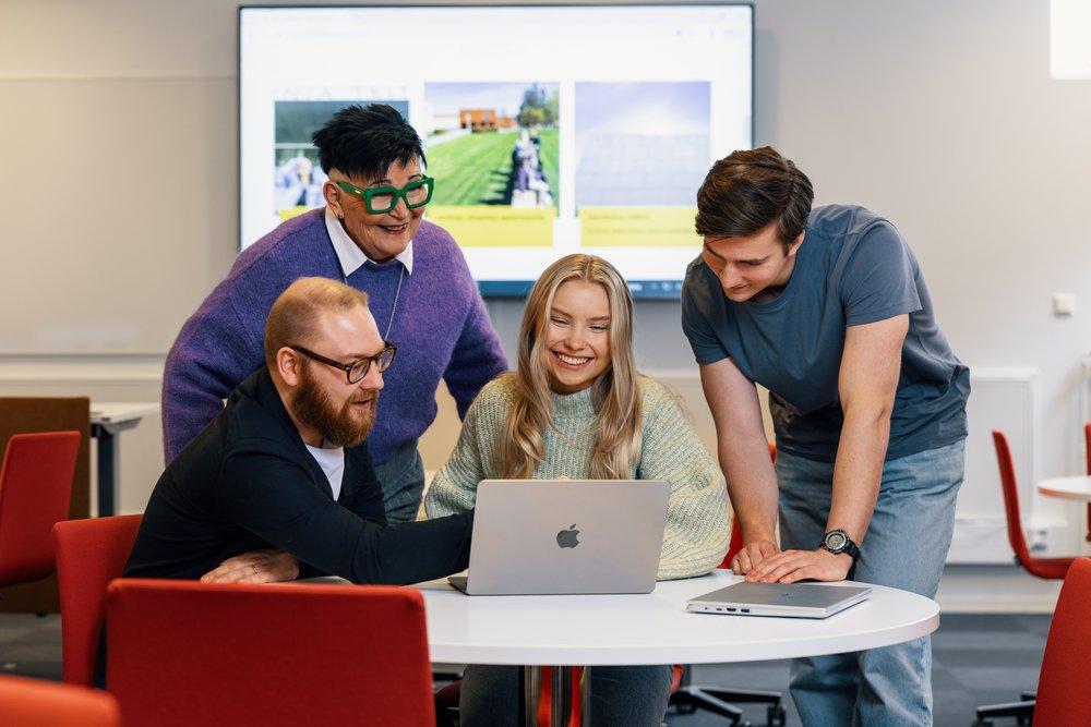 Viisi aikuista katsoo yhdessä tietokoneen näyttöä opetustilassa