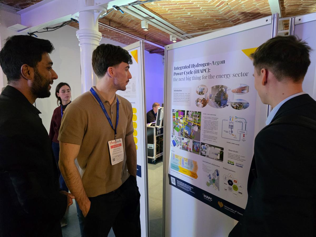 Kolme miestä tiedeposterin ympärillä